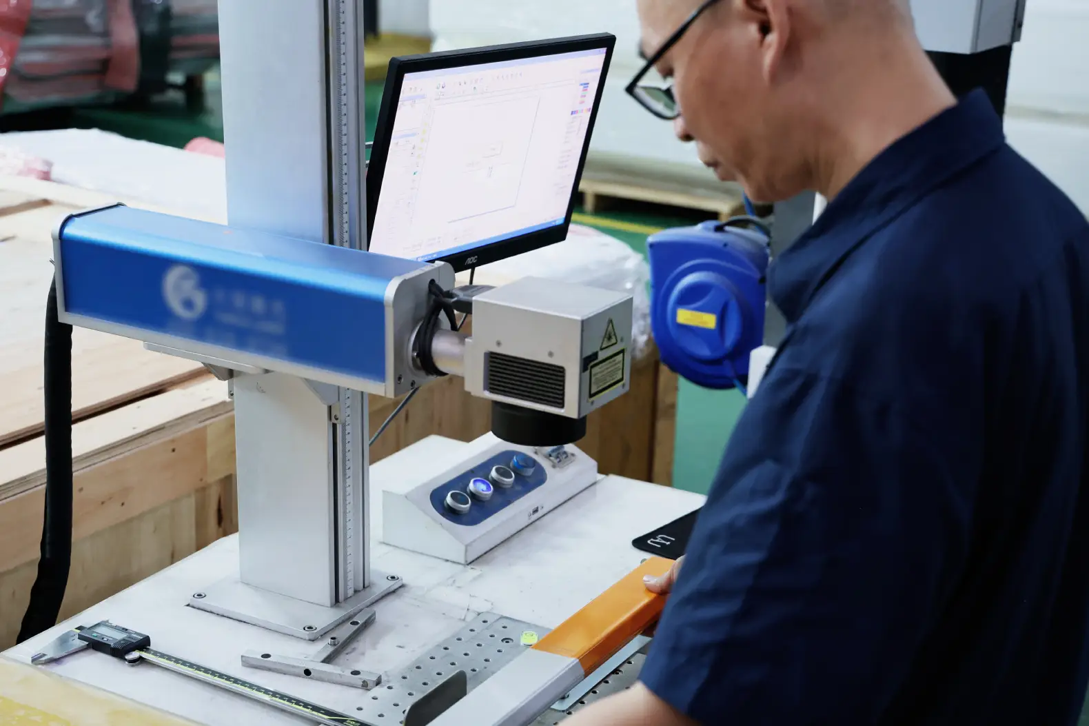 Operator running a fiber laser marking machine on a metal part at Boda
