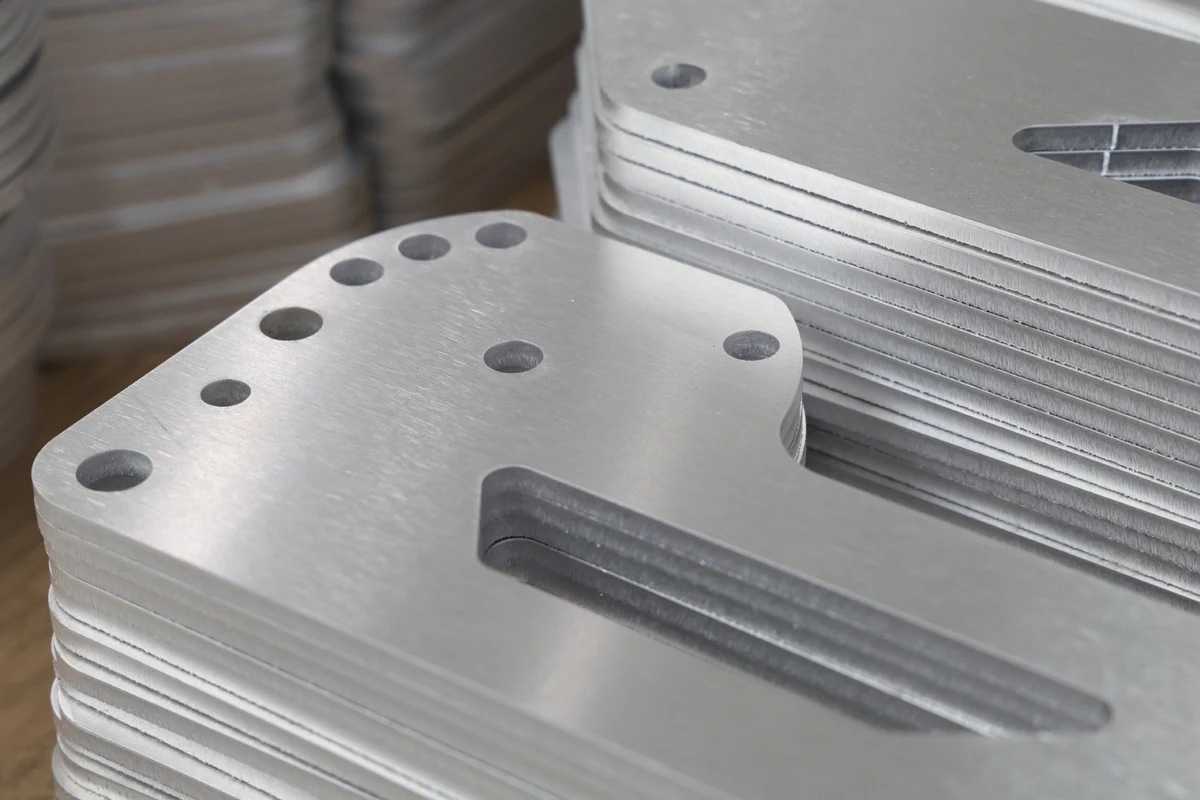 Stack of identical laser cut sheet metal parts with holes, slots and rounded corners