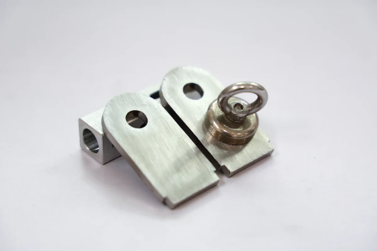 Small pot magnet clinging to a stack of small 304 stainless steel brackets with a formed tab