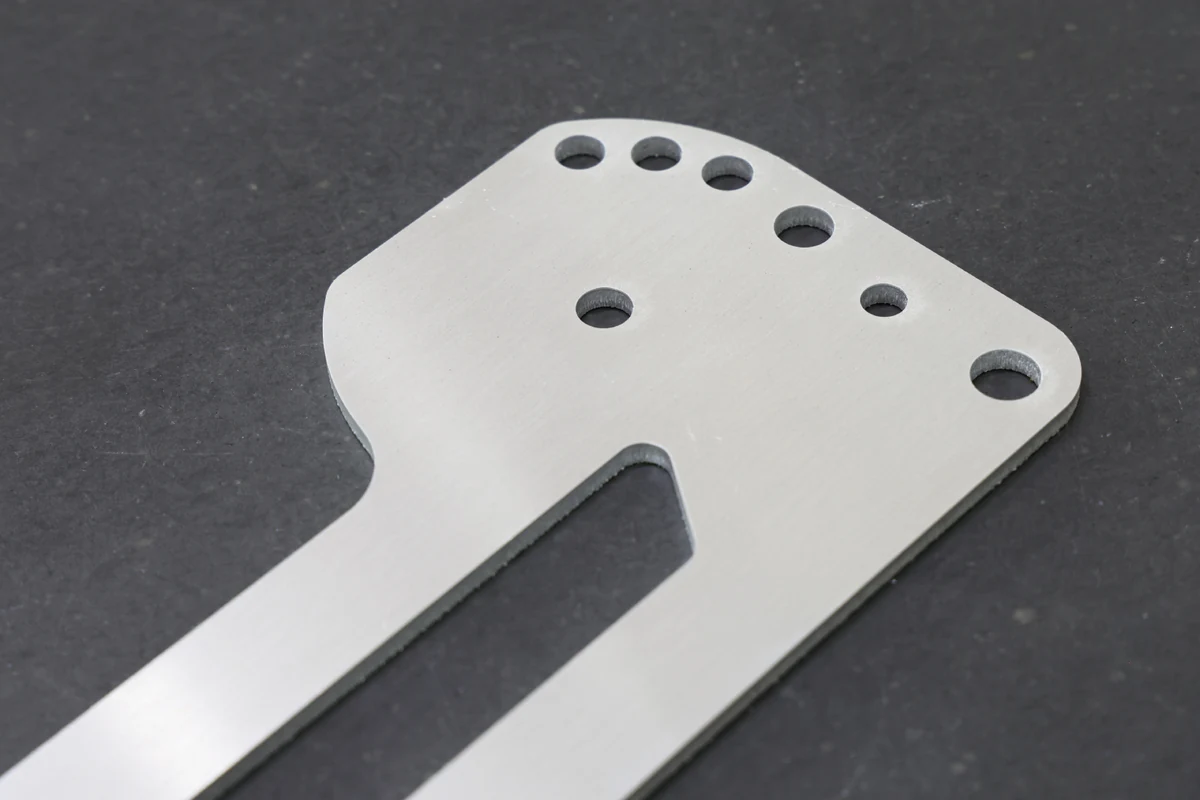 Laser cut sheet metal part with a row of holes, a long slot and rounded inside corners