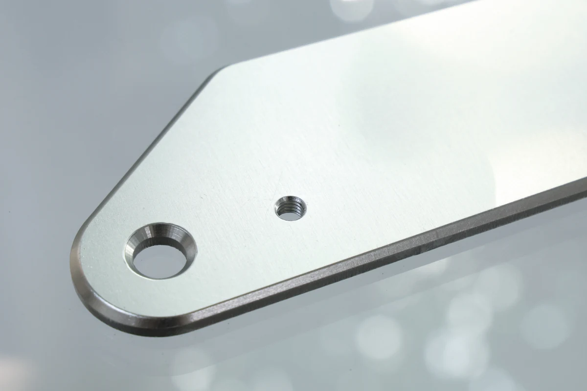 Laser cut sheet metal part with a countersunk hole and a tapped threaded hole near its rounded end
