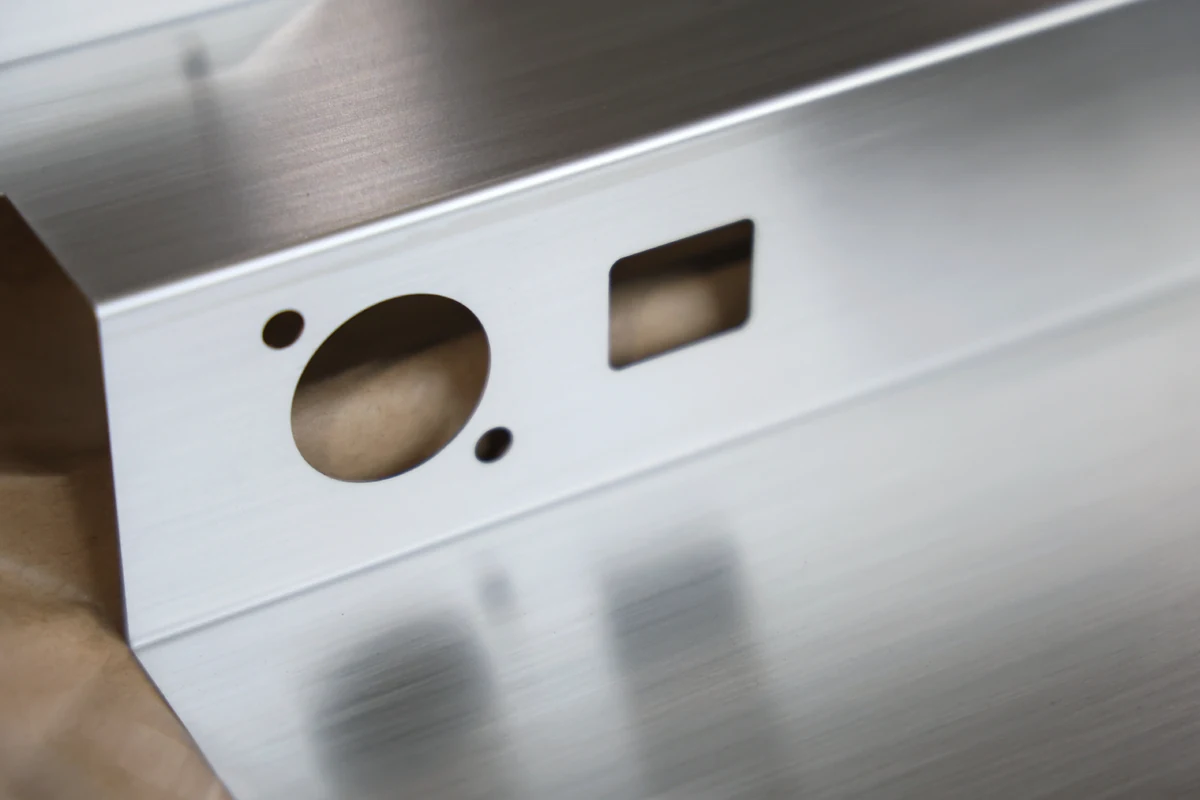 Formed brushed 316 stainless steel part with laser-cut round and rectangular cutouts