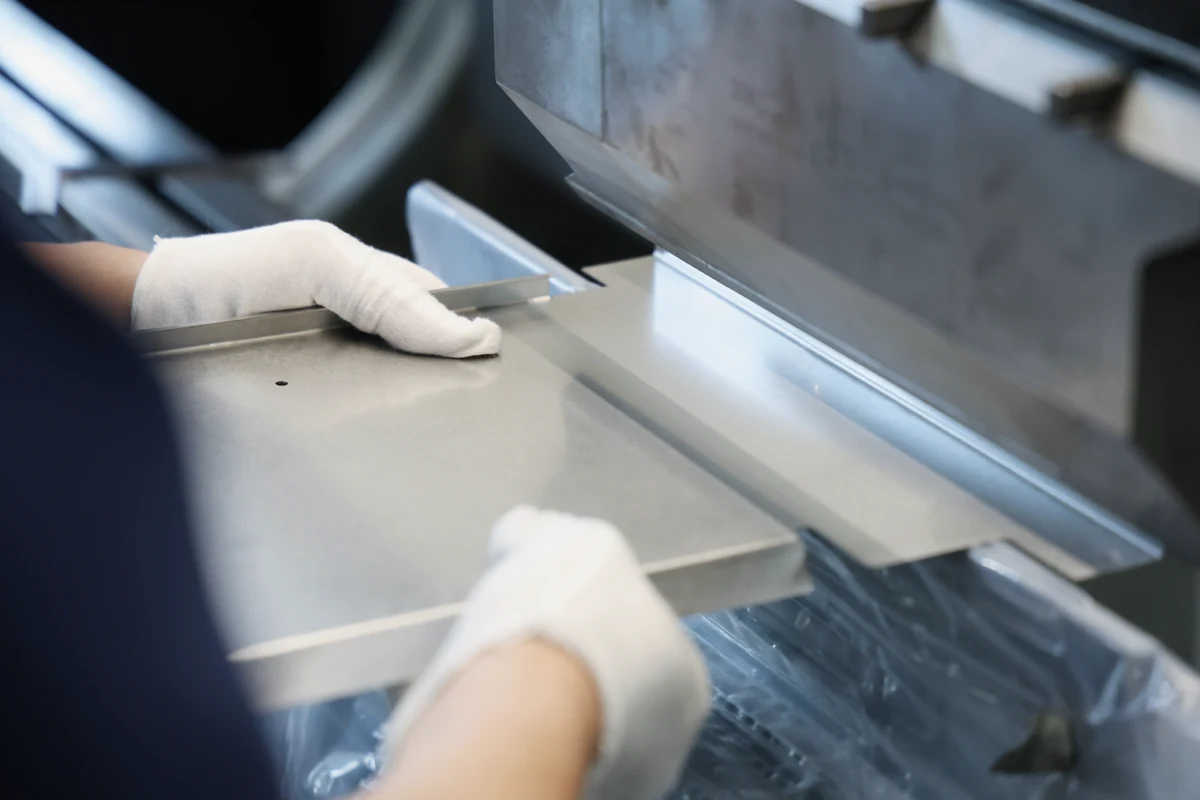 Operator in gloves forming a stainless steel sheet on a press brake